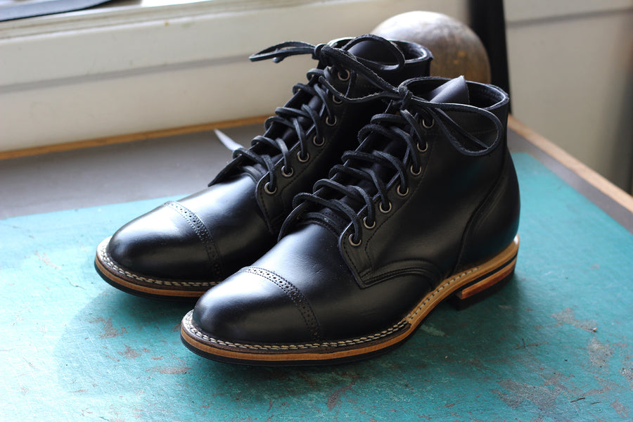 A pair of black boots displayed on a table.
