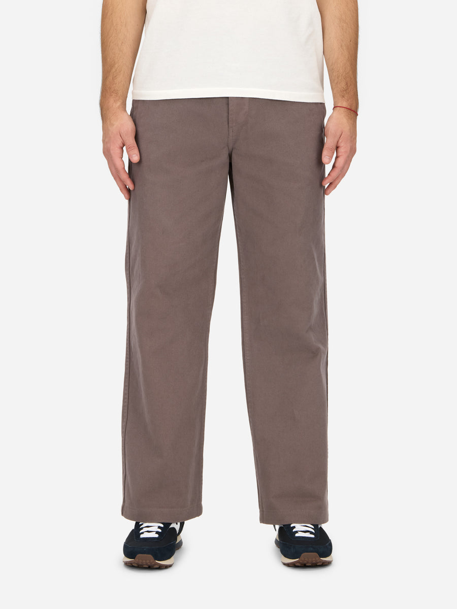 A person standing, wearing the Work Pant in a tobacco twill fabric, displaying a wide leg fit and high rise.