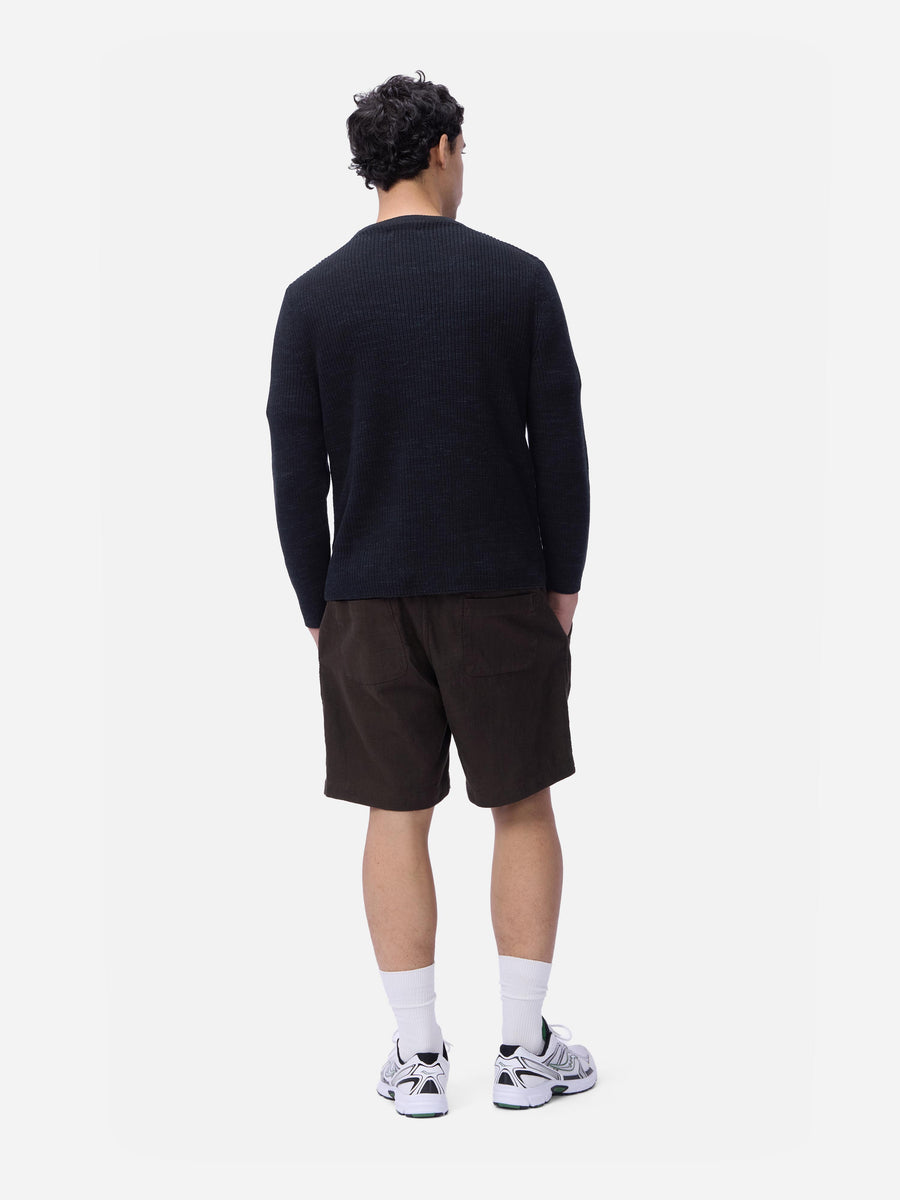 Person wearing a black sweater and dark shorts on a white background