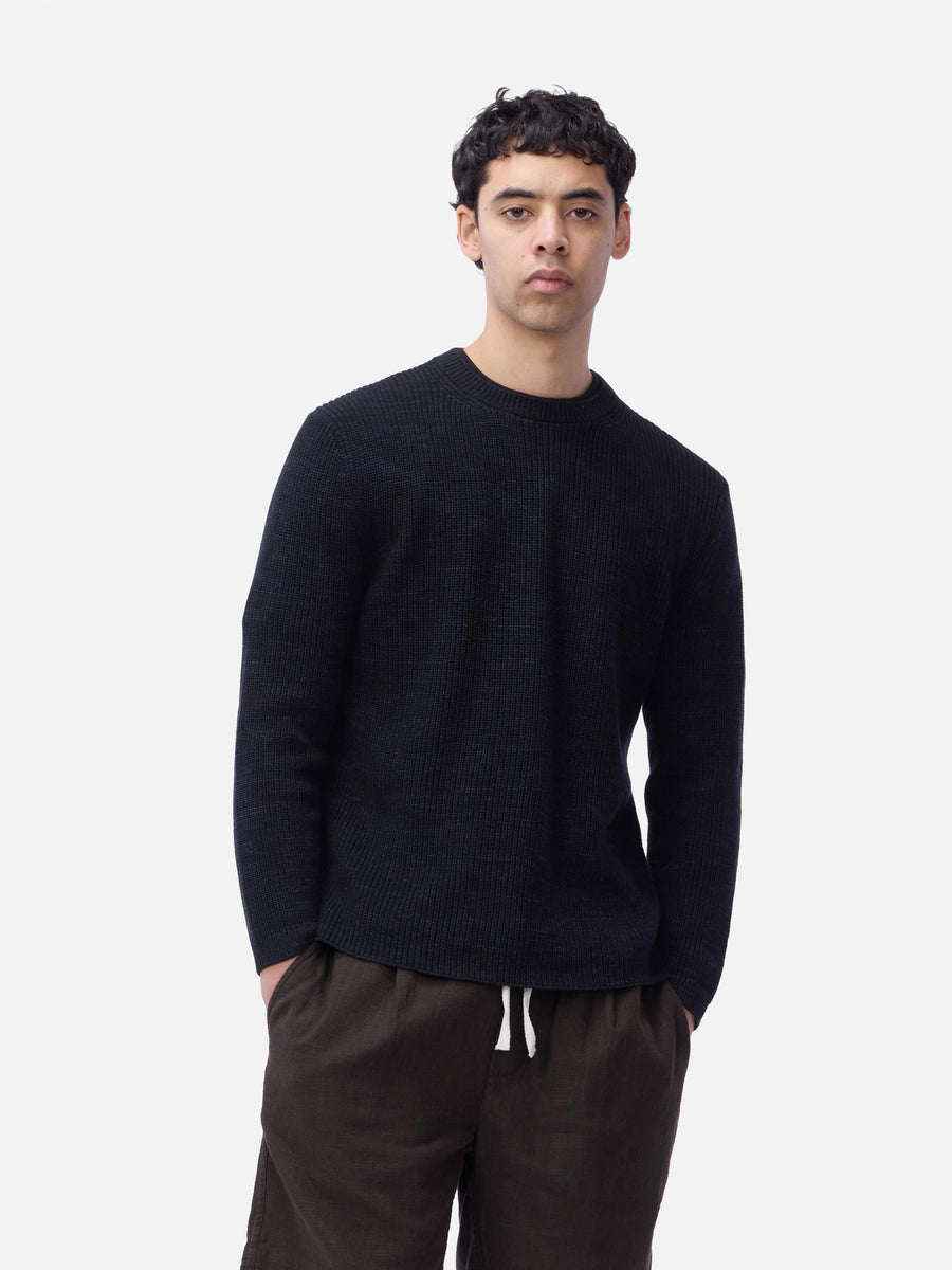 Man wearing a black sweater and brown pants on a white background