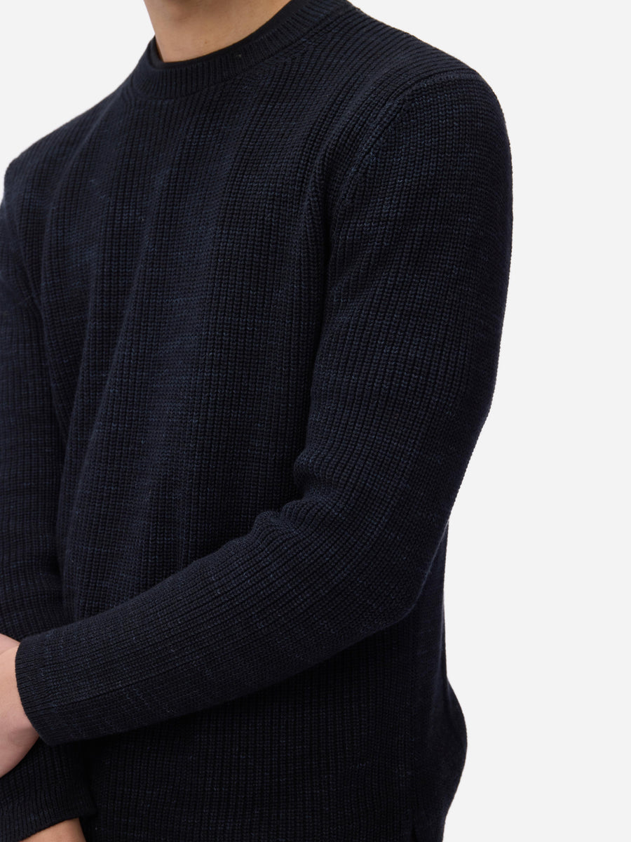 Dark blue ribbed sweater worn by a person on a white background