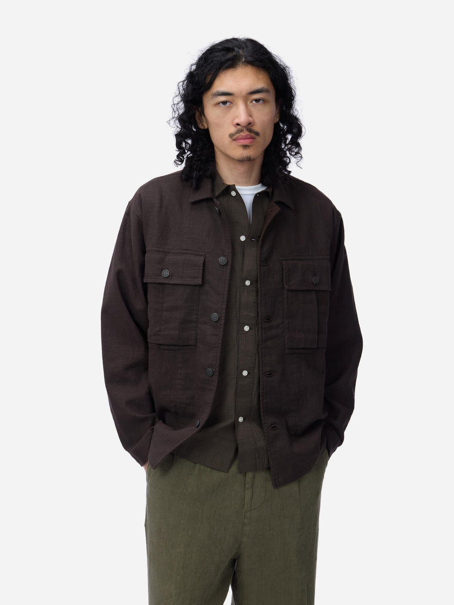 Man wearing a brown jacket with multiple pockets on a white background