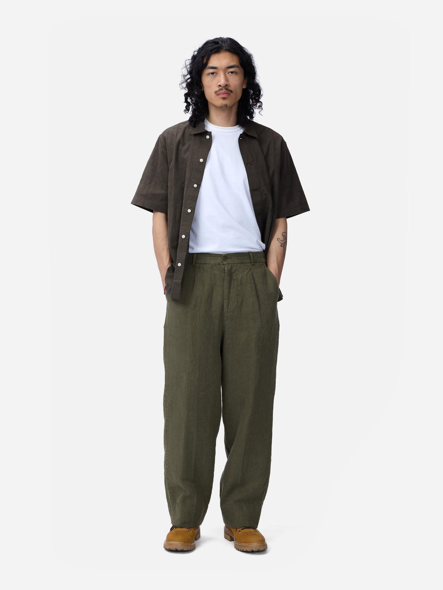 Man wearing a brown shirt, white t-shirt, green pants, and brown shoes on a white background