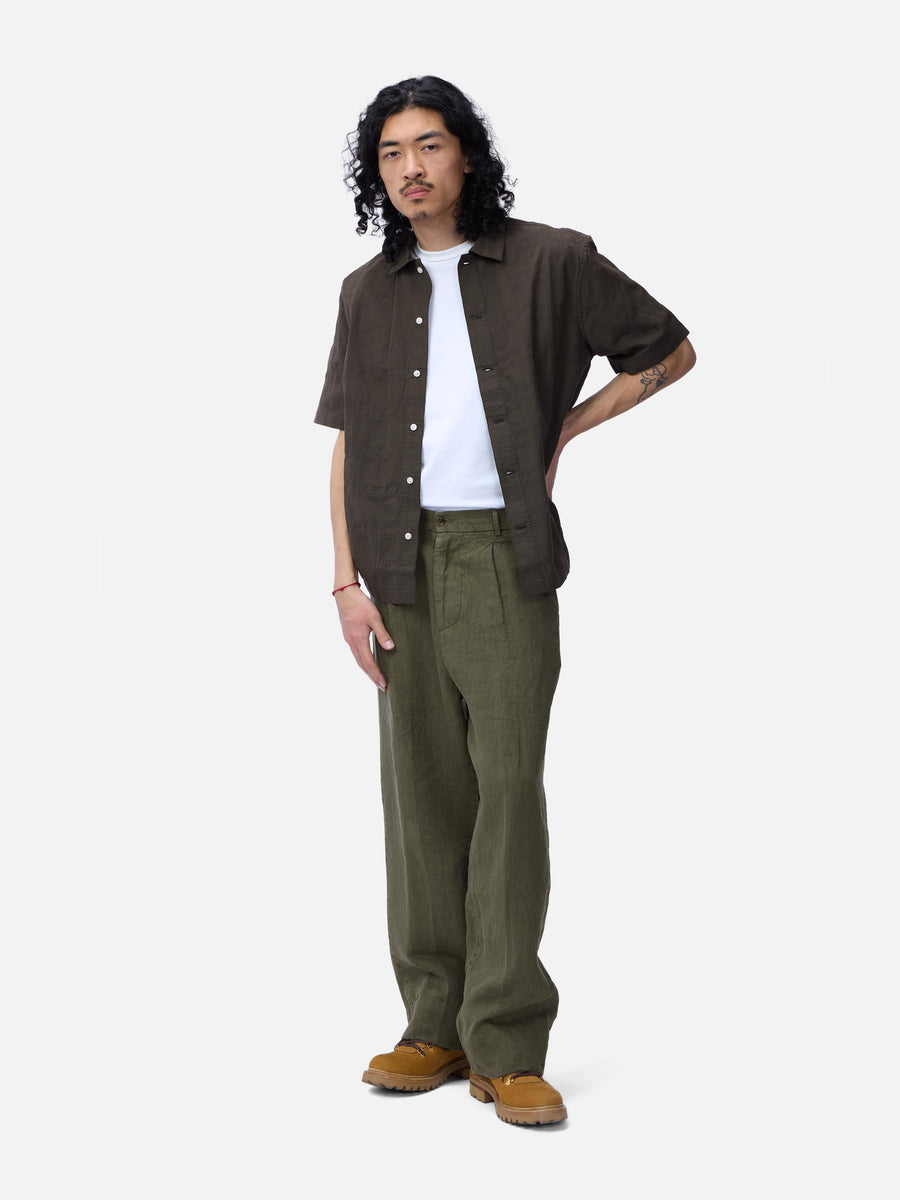 Man wearing a brown shirt, white t-shirt, and green pants on a white background