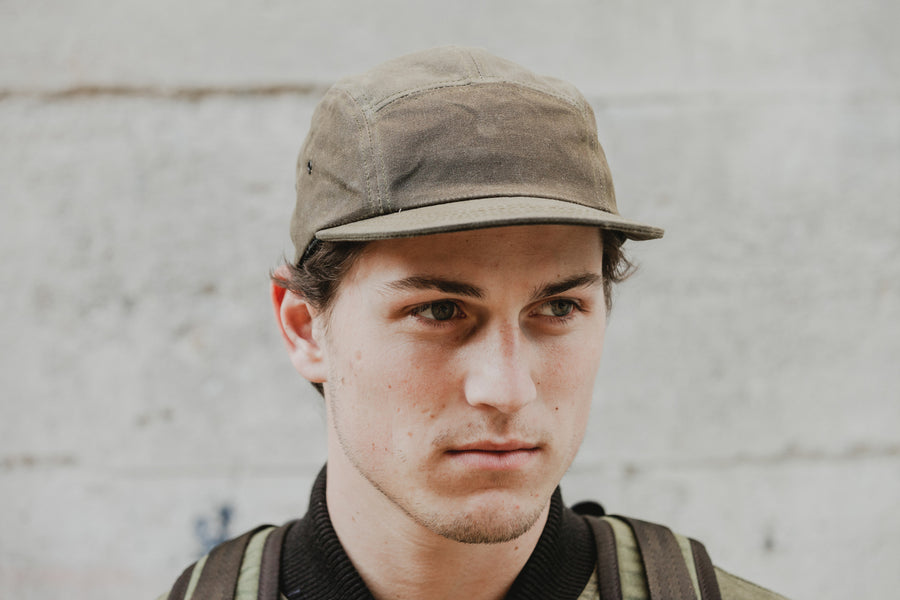 Front-facing shot of a model wearing the brown waxed canvas 5-panel.